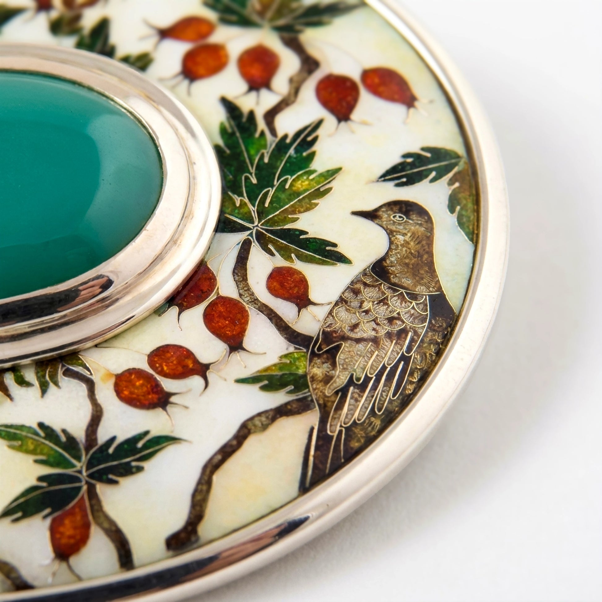 Decorative brooch with bird and floral design on a white background